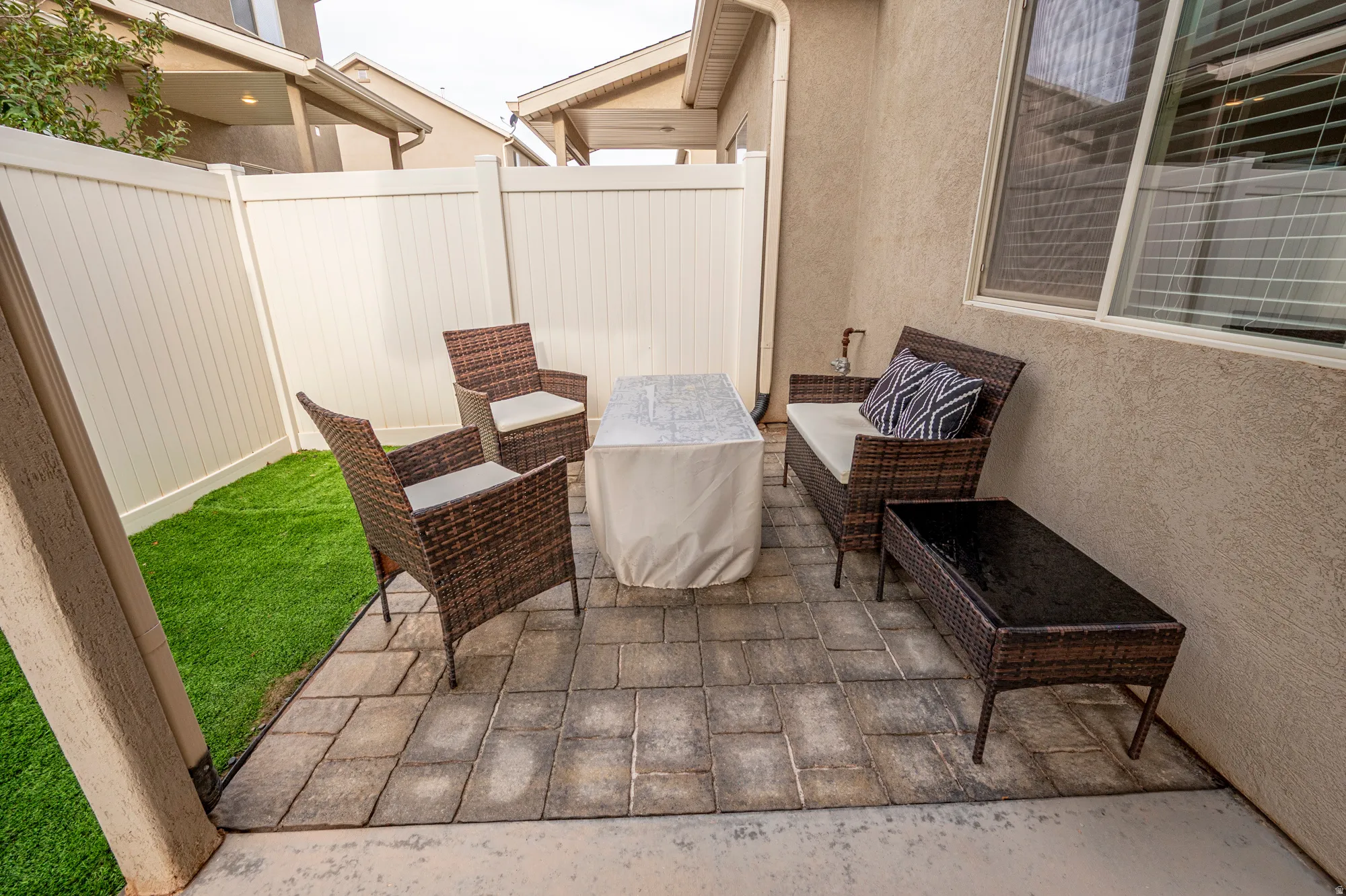 Outdoor patio featuring paver flooring, privacy fencing, and turf landscaping