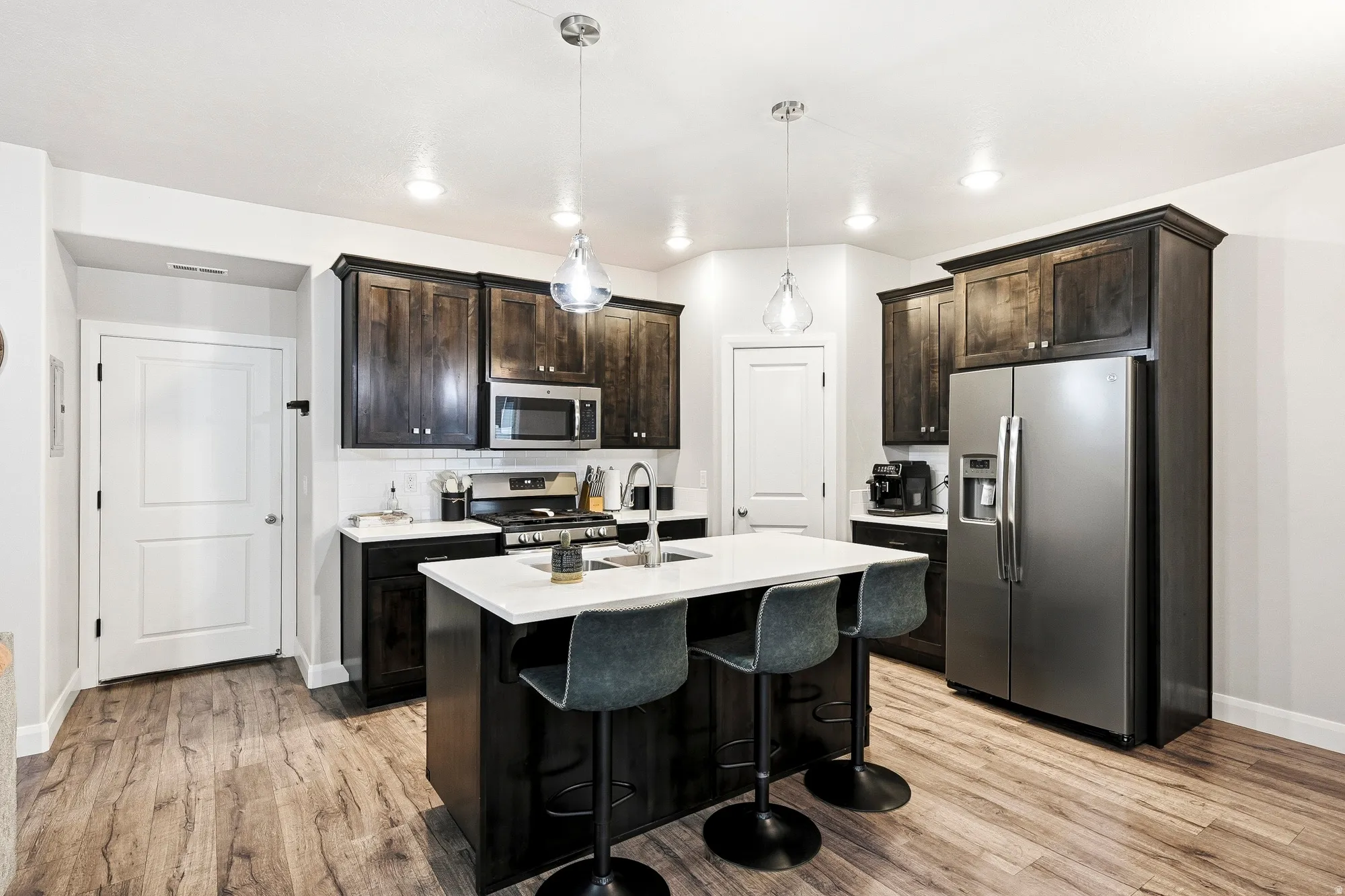 Kitchen featuring wood-finish flooring, dark wood cabinetry, white subway tile backsplash, and a center island with a white countertop