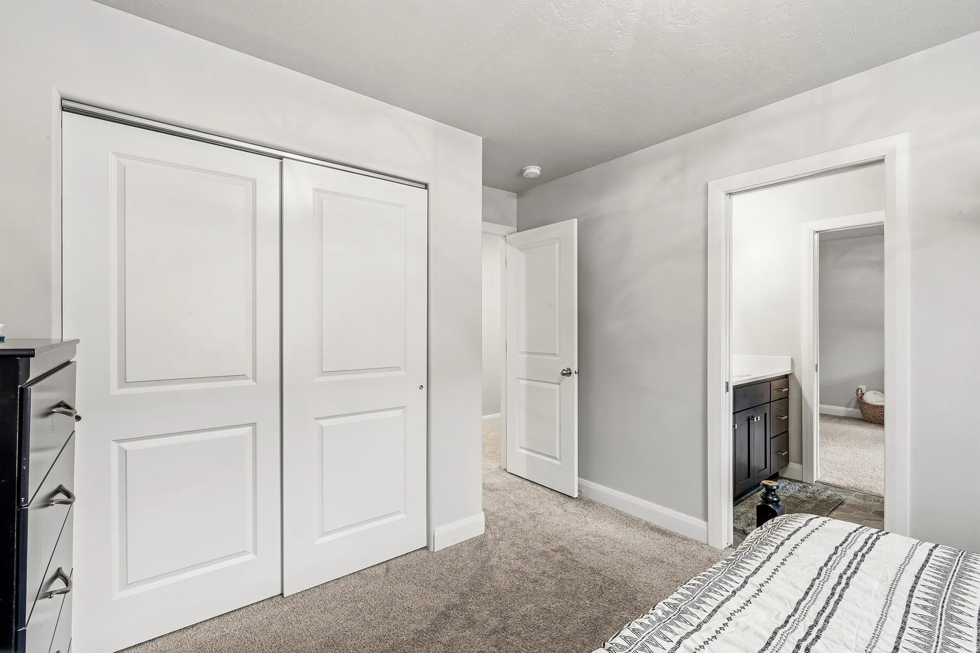 Bedroom featuring light gray wall paint, gray carpet, and white bi-fold closet doors