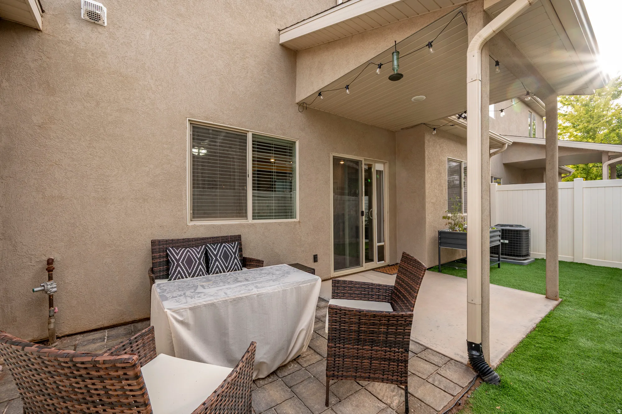 Back patio with a partial covered area, a sliding glass door, and a privacy fence