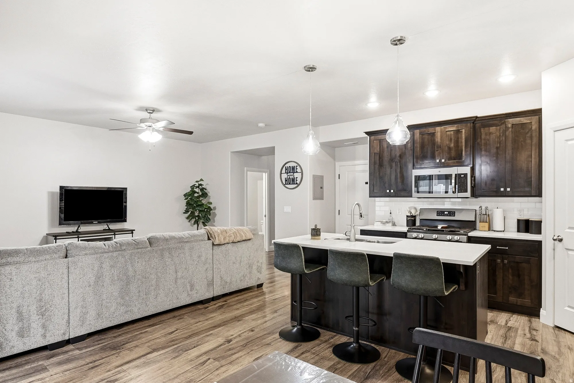 Kitchen island with seating, stainless steel appliances, dark wood-finish cabinetry, subway tile backsplash, and recessed lighting