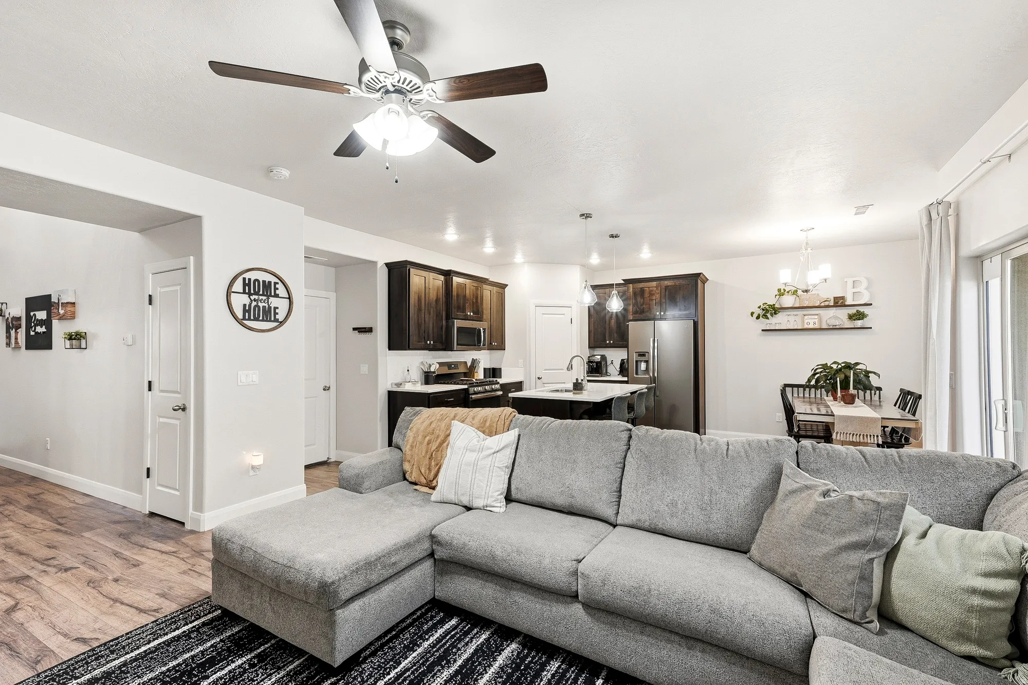 Wood-finish flooring throughout, ceiling fan with integrated lighting, recessed lighting, white trim and doors, and a sliding glass door