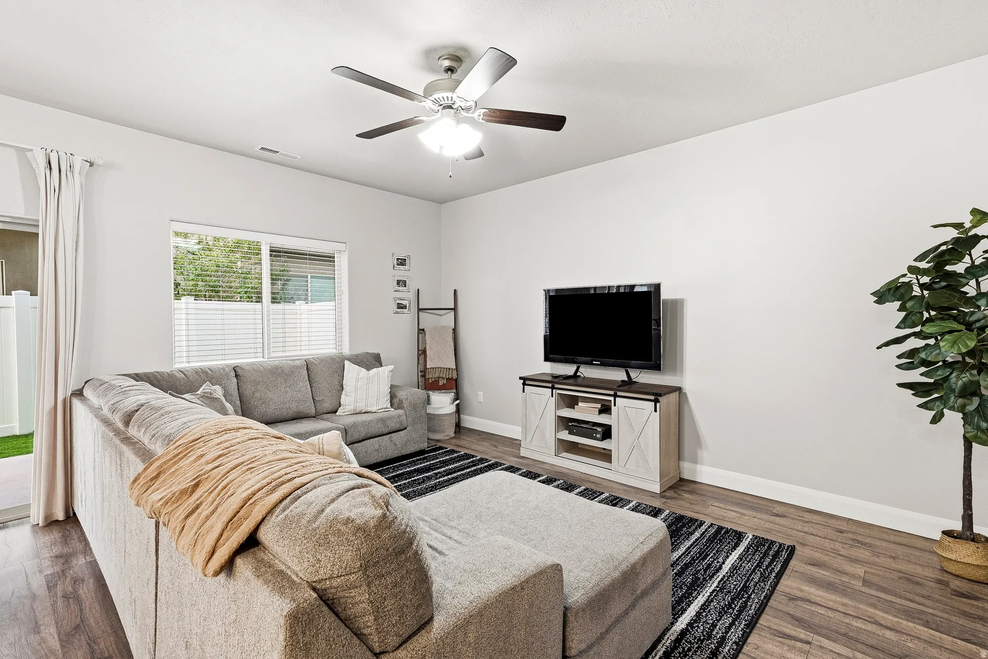 Wood-finish flooring, ceiling fan, white window blinds, and sliding glass door