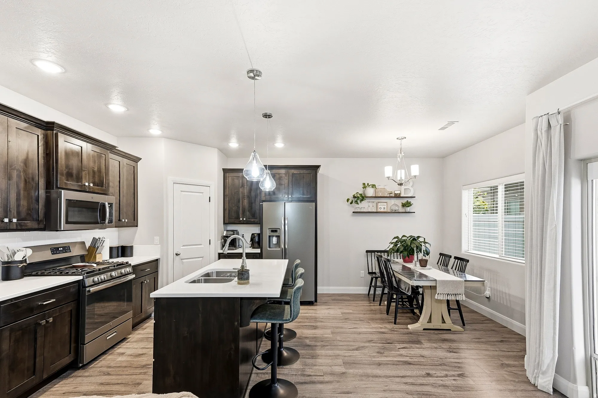 Kitchen featuring dark wood-finish cabinetry, stainless steel appliances, a center island with sink, and light-toned countertops