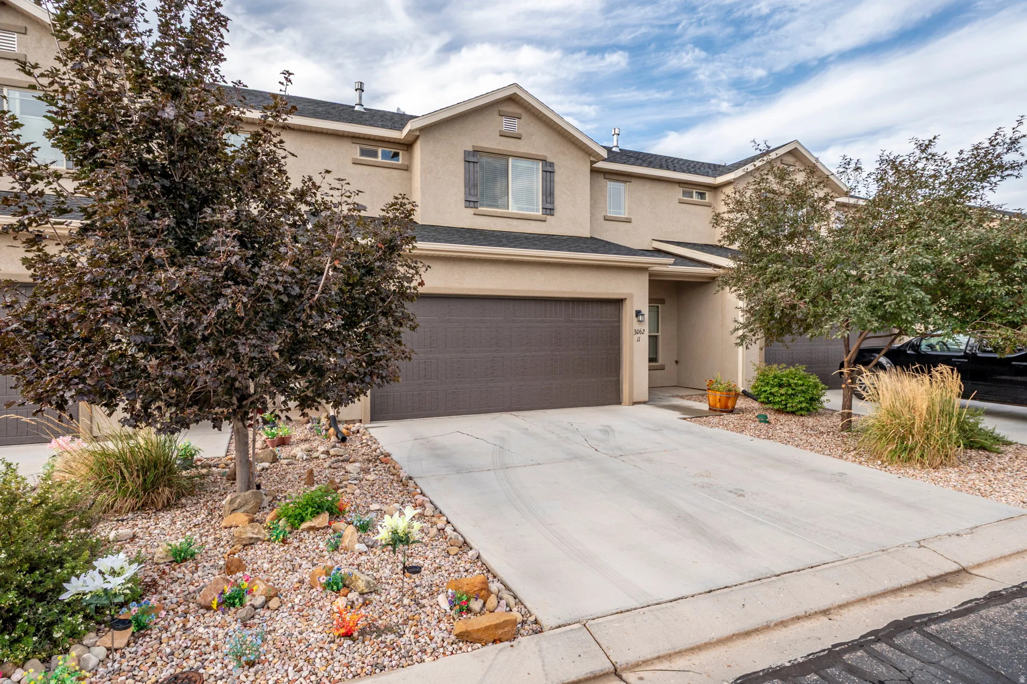 Stucco exterior with multiple windows, attached garage, and paved driveway