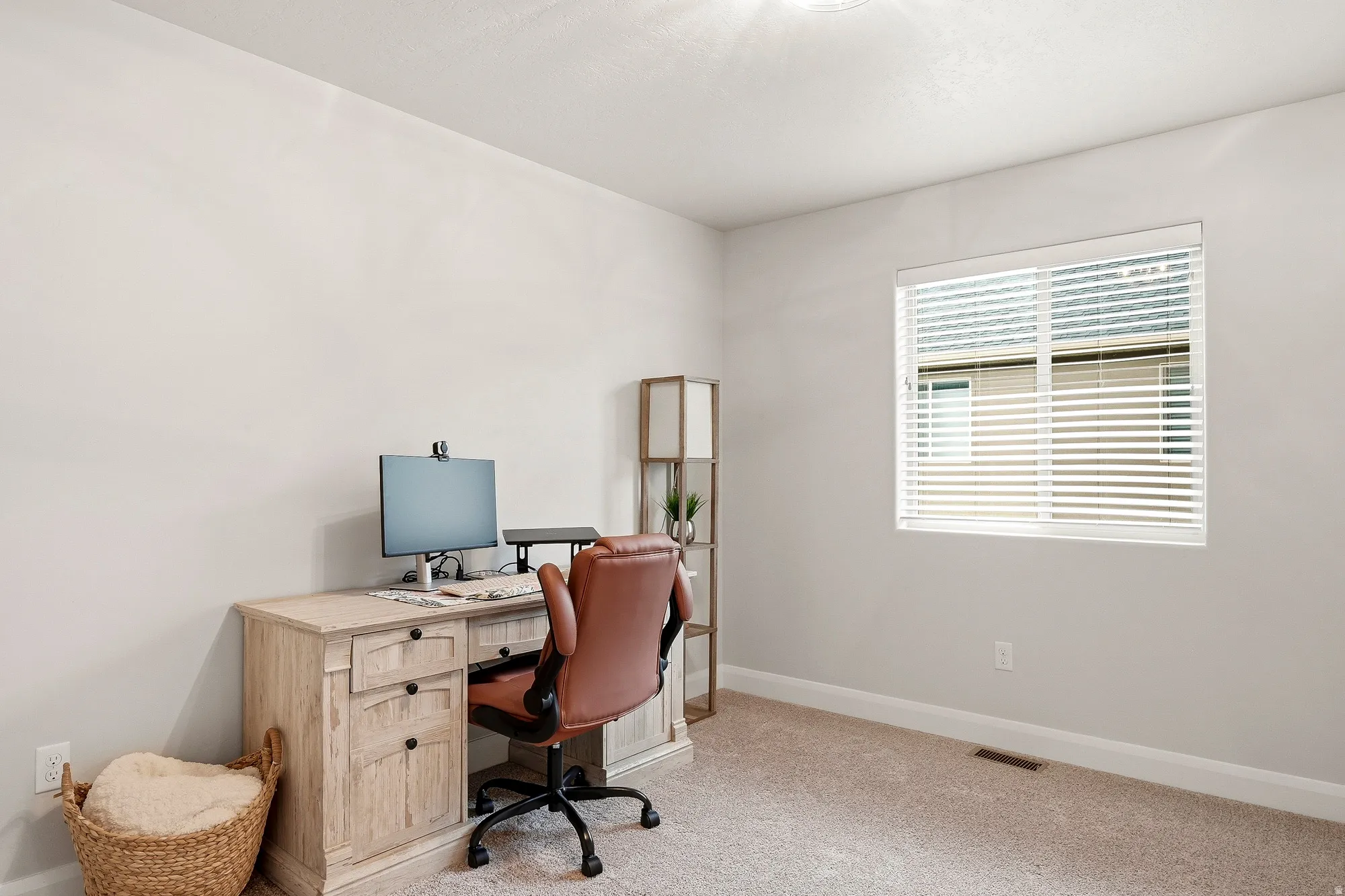 Neutral wall paint, light-colored carpeting, and a window with blinds