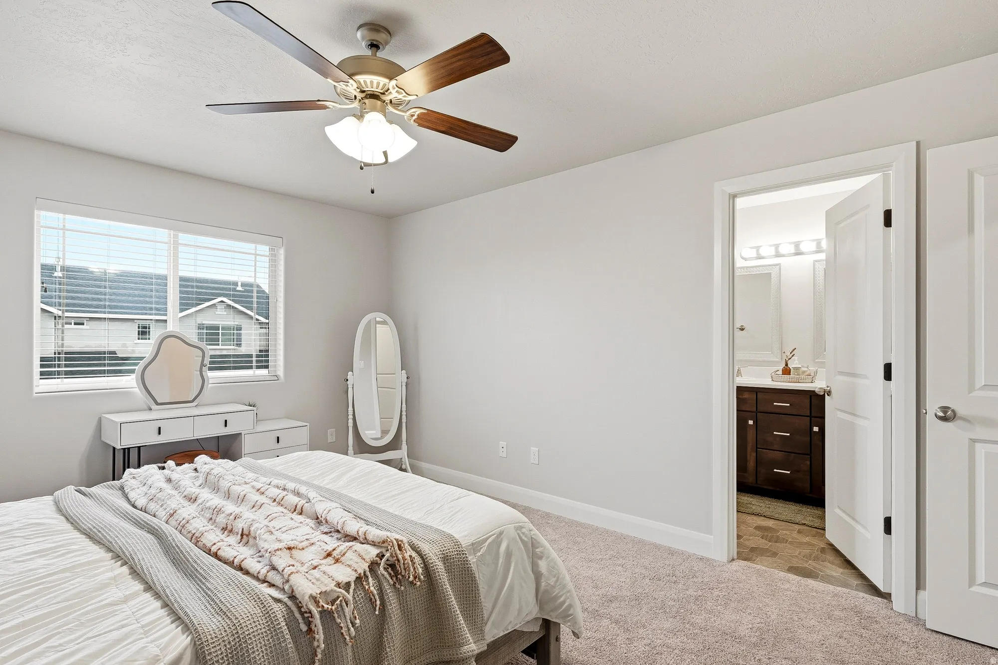 White walls, carpet flooring, and a ceiling fan with integrated lighting