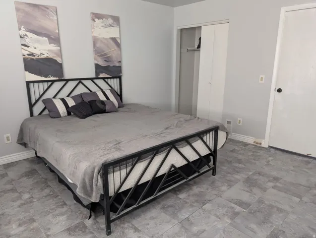 Grey-toned flooring, light grey walls, and a built-in closet with bi-fold doors