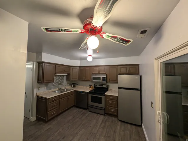 Kitchen featuring wood-finish flooring, brown cabinetry, stainless steel appliances, and a tiled backsplash
