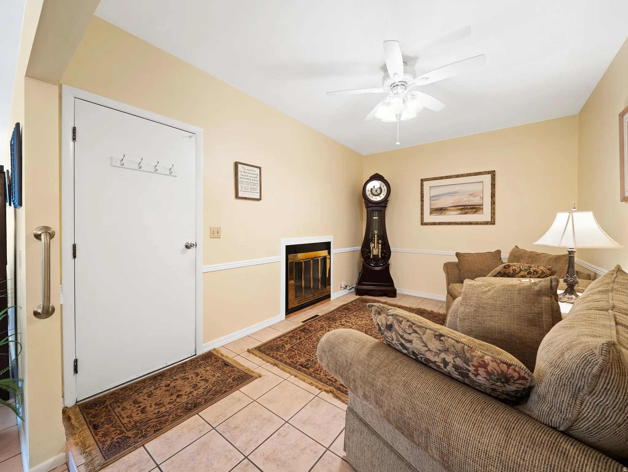Tiled flooring, white ceiling fan with integrated lighting, chair rail molding, and an electric fireplace insert