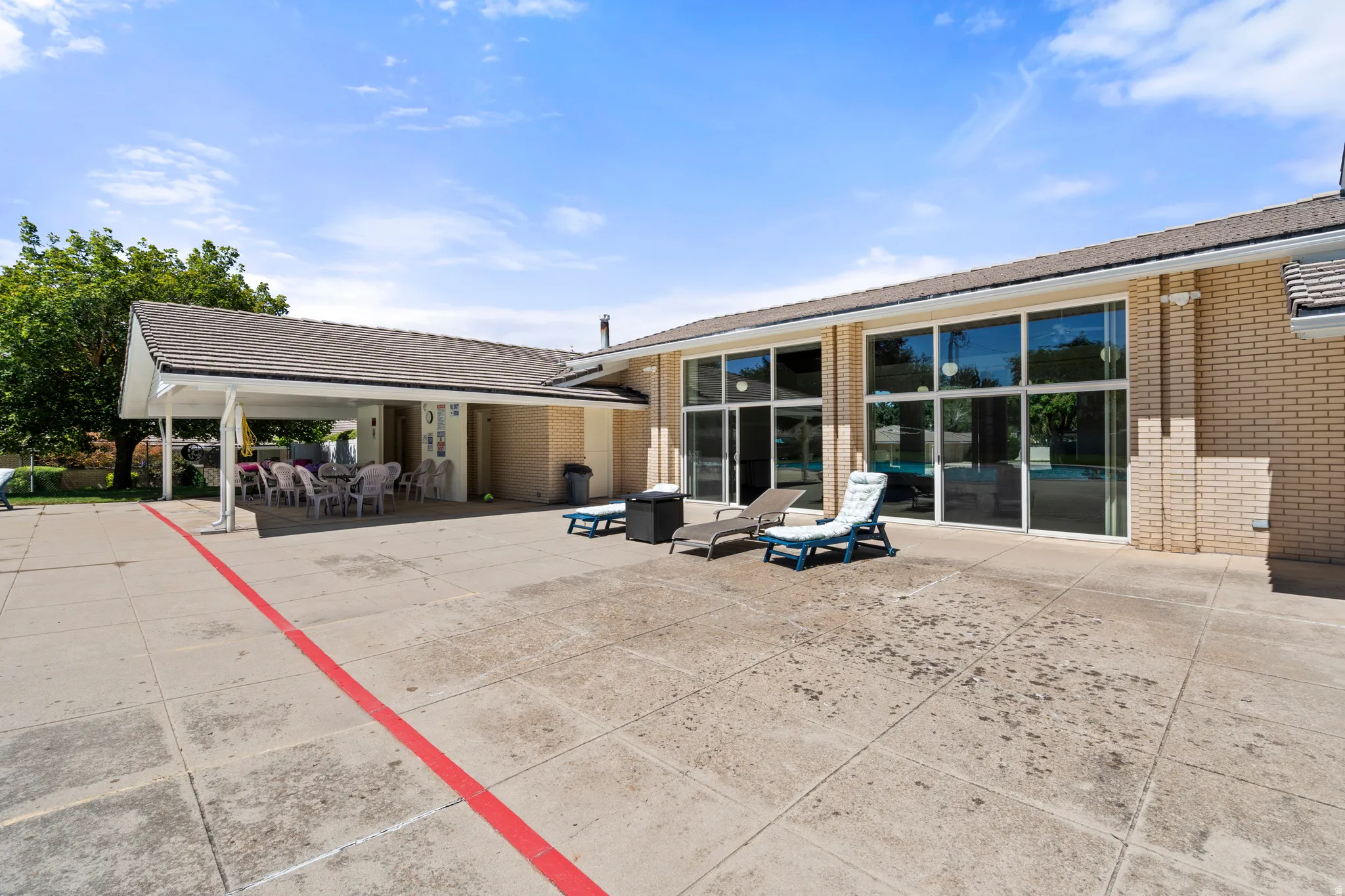 Expansive patio with a covered outdoor dining area, a brick exterior, and large glass windows