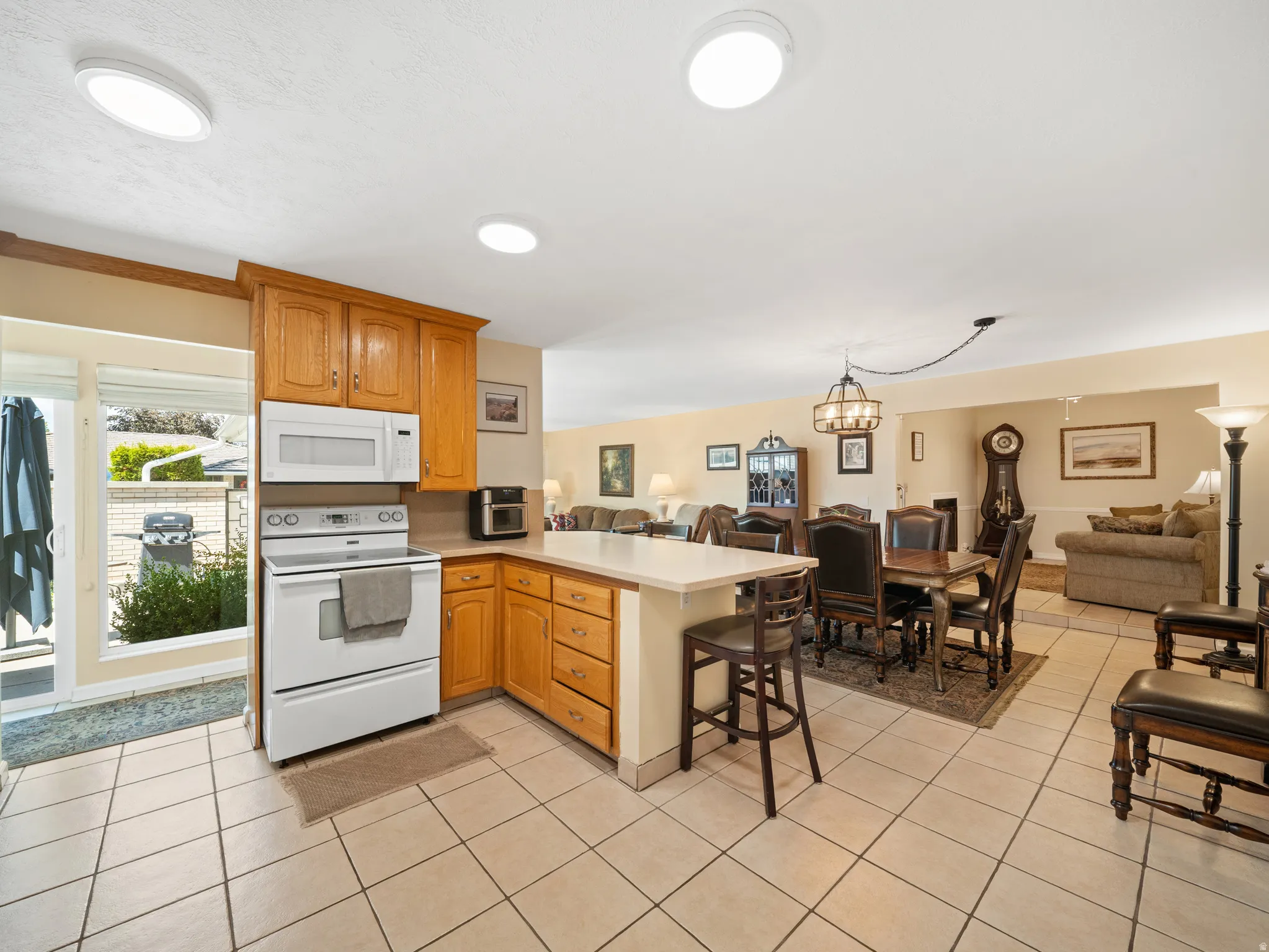 Kitchen featuring wood cabinetry, white appliances, a light-toned countertop, and tile flooring
