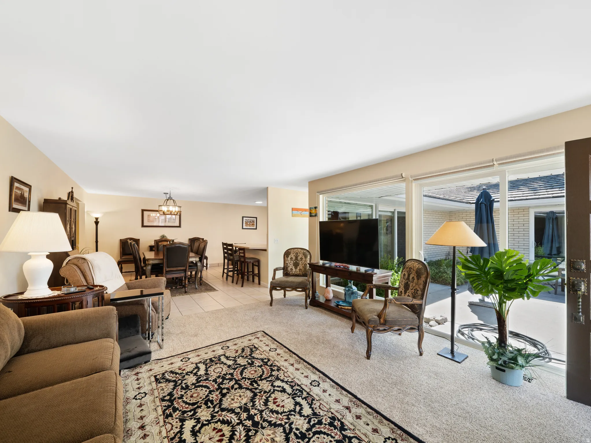 Expansive living area with large glass sliding doors, neutral carpeting, and tiled dining area
