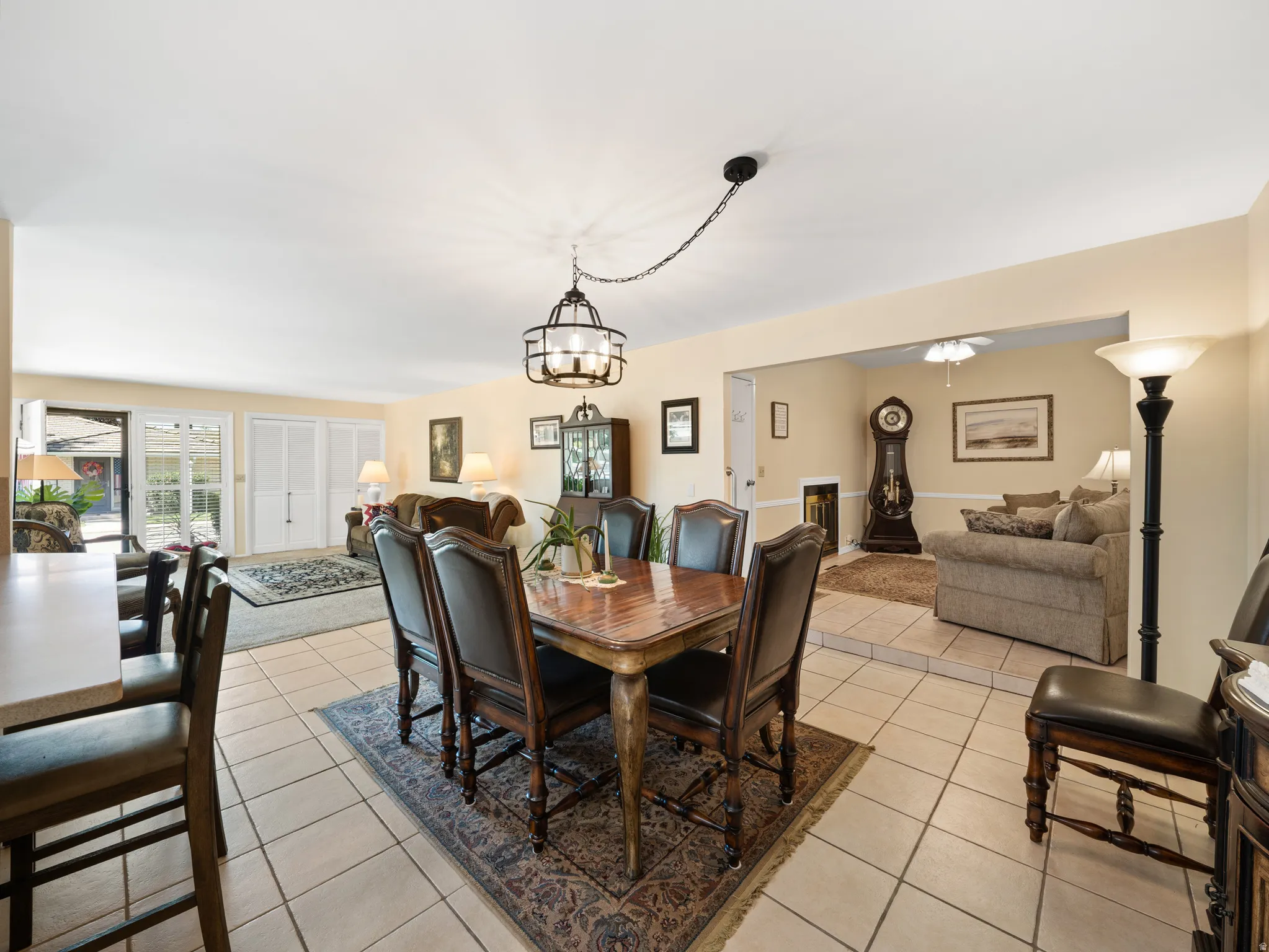 Tile flooring with a decorative area rug, leading to a living space with French doors, and a separate room with a ceiling fan