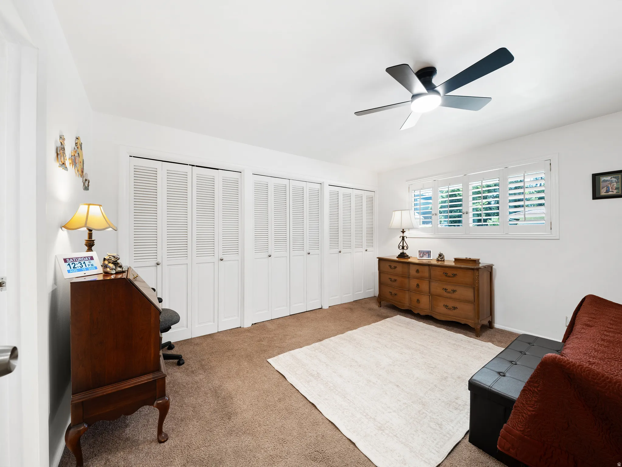 Recessed window with plantation shutters, ceiling fan with integrated lighting, and carpeted flooring