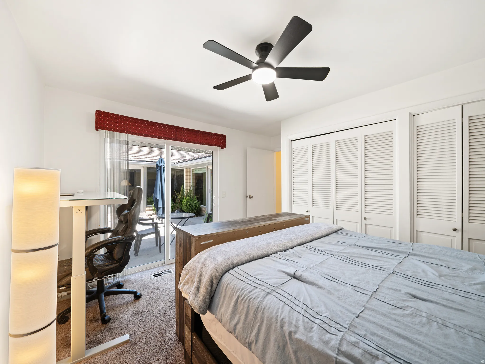 Sliding glass patio door with an outdoor patio, ceiling fan with integrated lighting, and louvered bifold closet doors