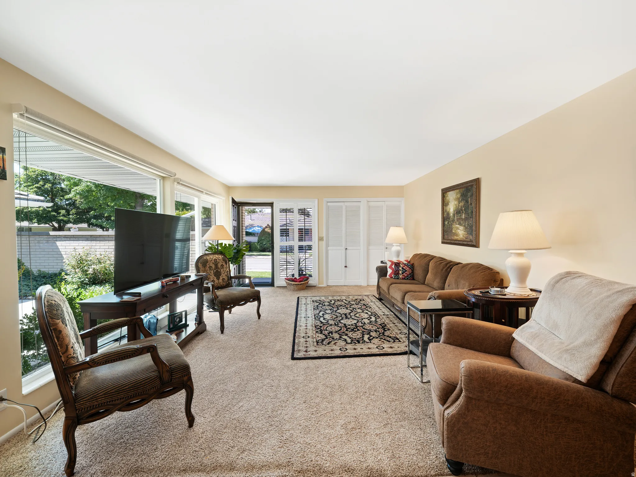 Expansive windows, neutral wall tones, and carpeted flooring