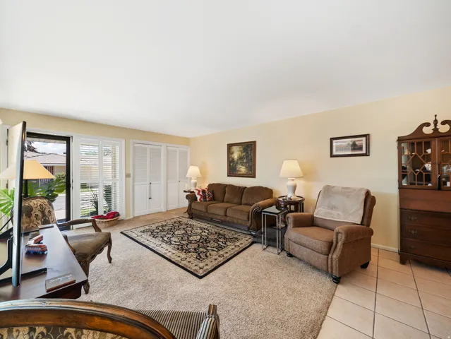 Spacious living room with warm yellow walls, tile flooring, and multiple windows providing natural light