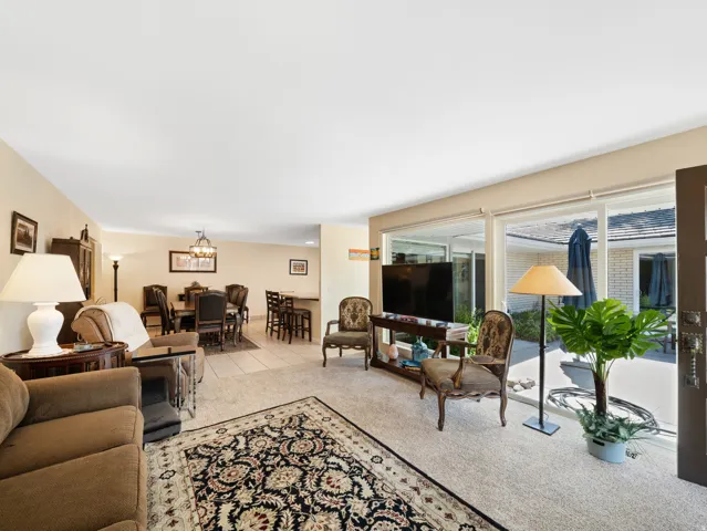 Expansive living area with large glass sliding doors, neutral carpeting, and tiled dining area