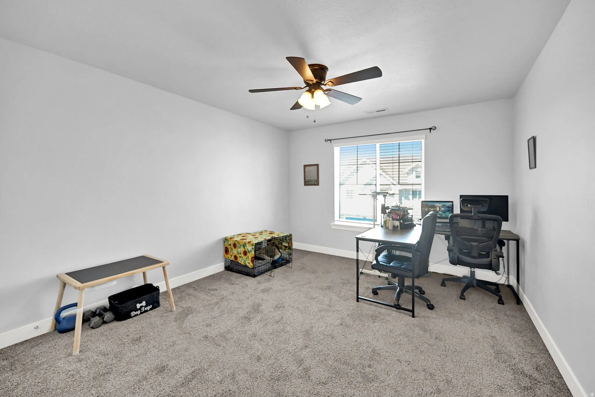 Carpeted room with a ceiling fan light fixture and a window featuring blinds