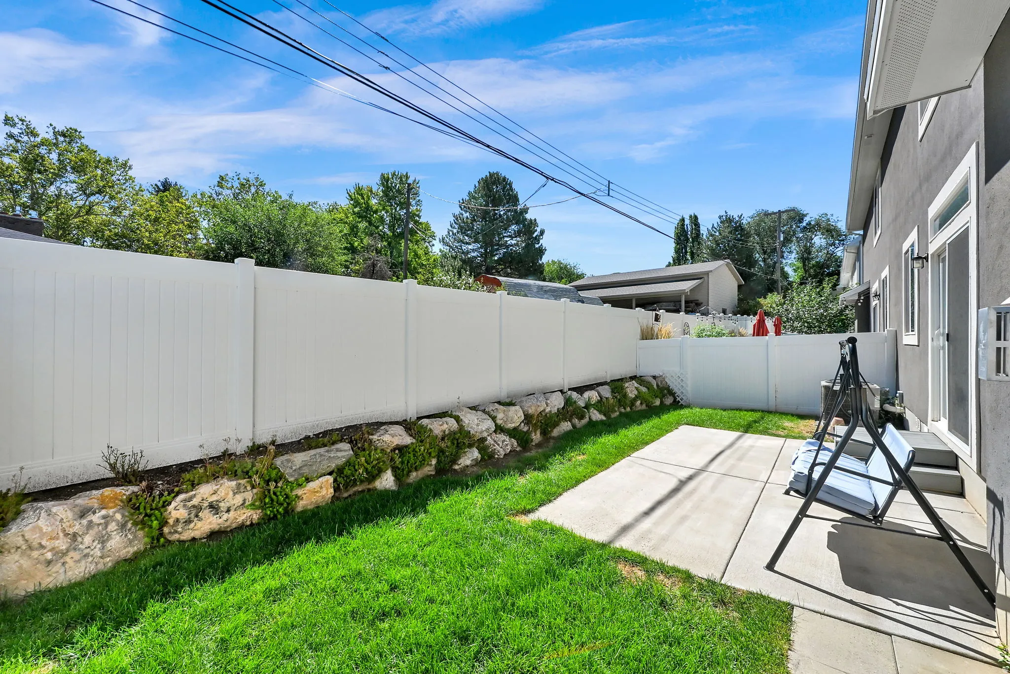 Private outdoor space featuring a concrete patio, green lawn, and white privacy fencing