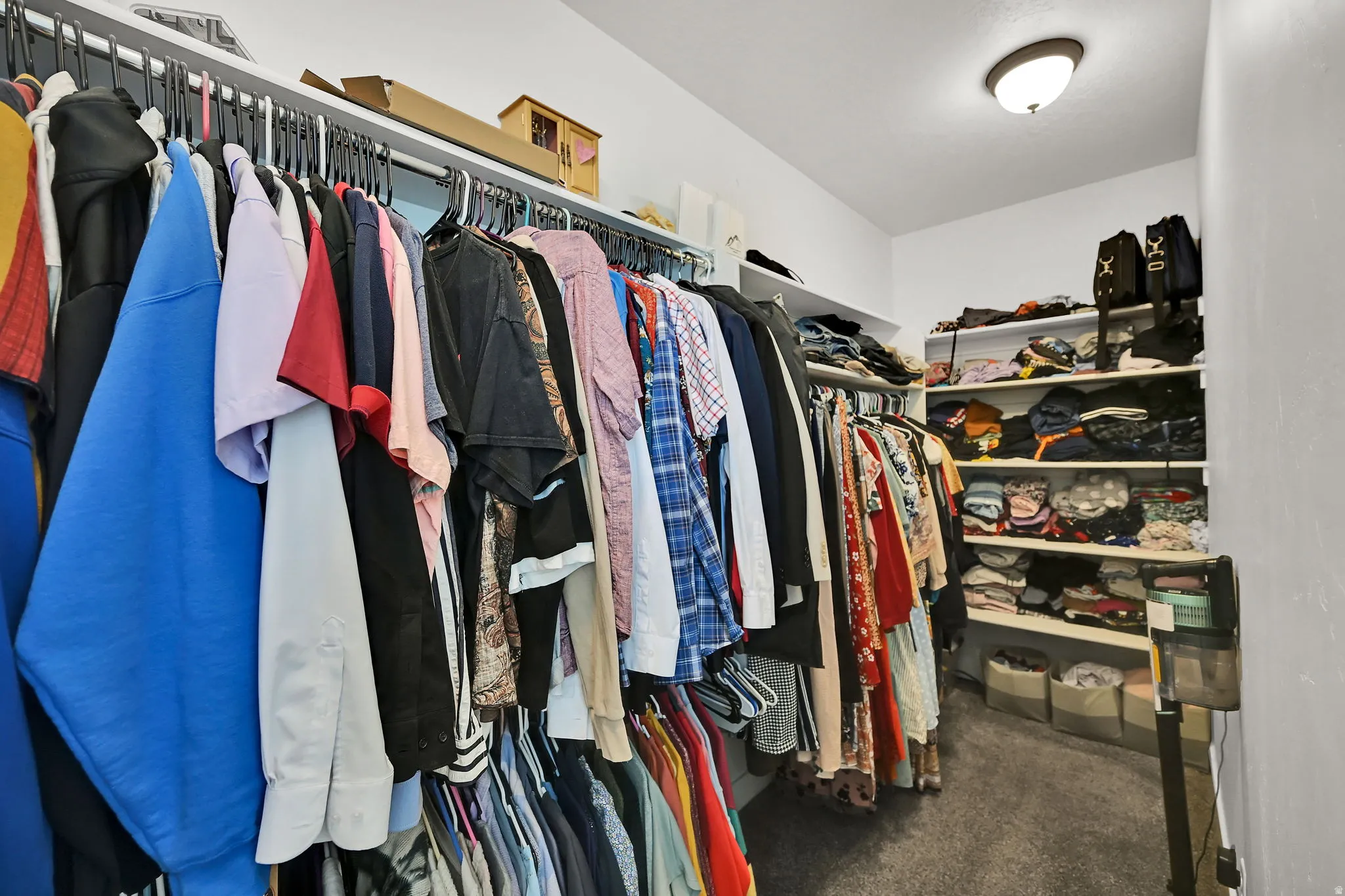 Expansive closet featuring multiple clothing rods, built-in shelving, white walls, and a flush-mount ceiling light