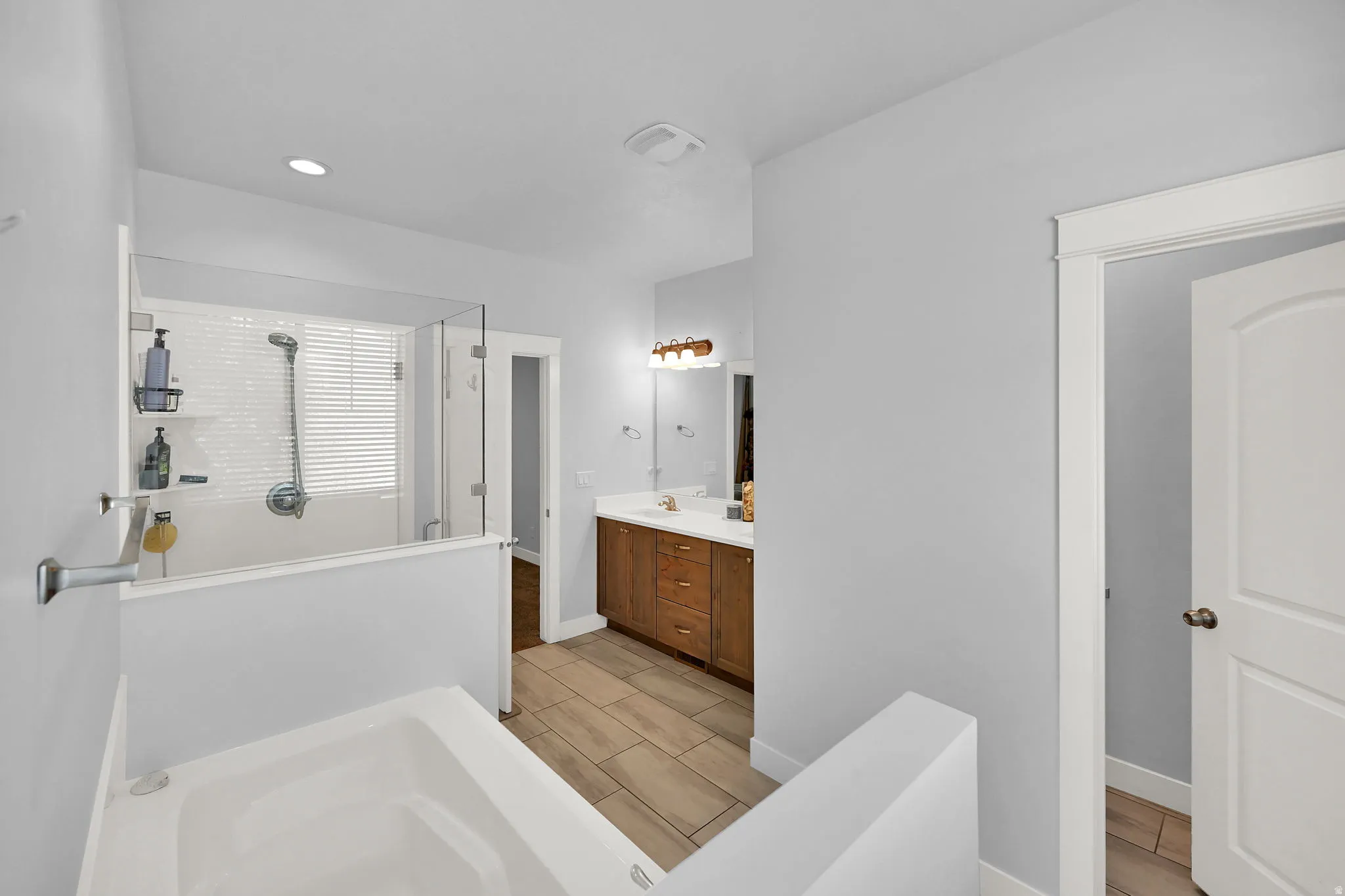 Soaking tub and glass-enclosed shower with white subway tile