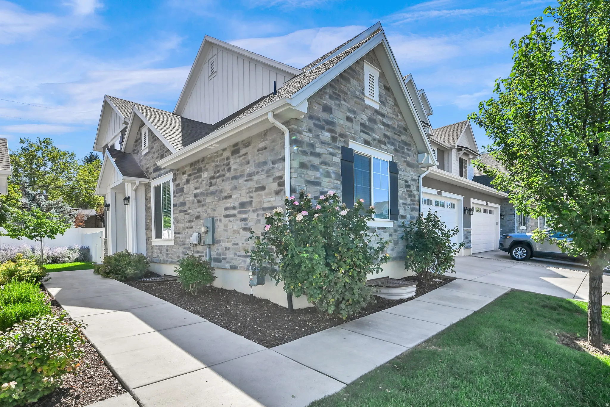 Stone veneer exterior with gabled roofline, multiple windows with dark shutters, and an attached two-car garage