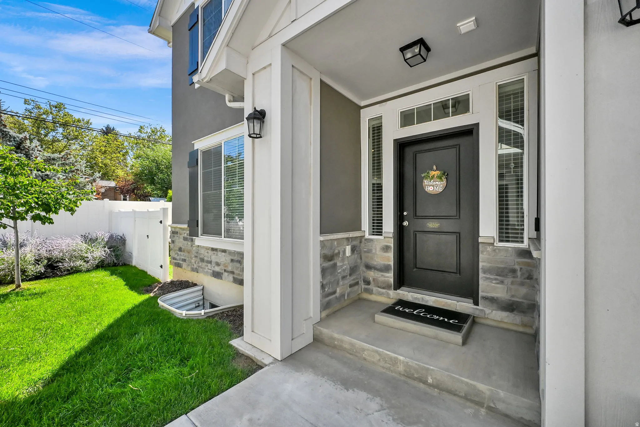 Stucco exterior with stone veneer accents, covered porch entry, transom window, and flanking sidelights