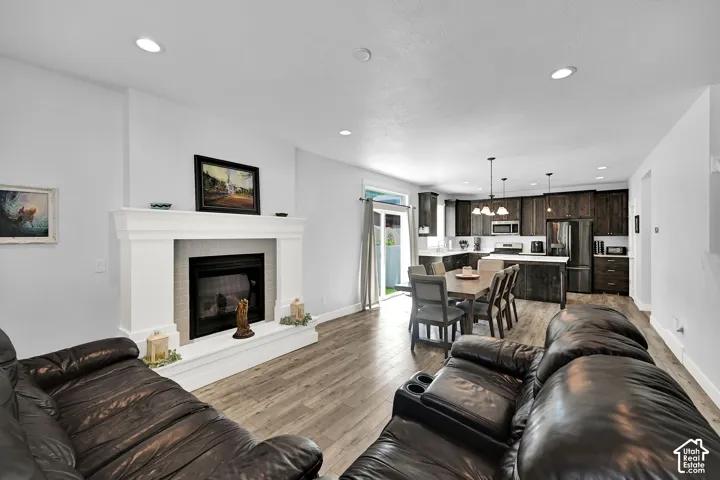 Living area with a fireplace featuring a white mantel, recessed lighting, wood-finish flooring, and sliding glass doors
