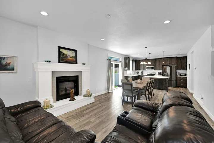 Living area with a fireplace featuring a white mantel, recessed lighting, wood-finish flooring, and sliding glass doors