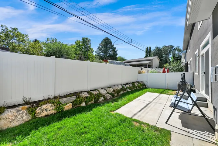 Private outdoor space featuring a concrete patio, green lawn, and white privacy fencing
