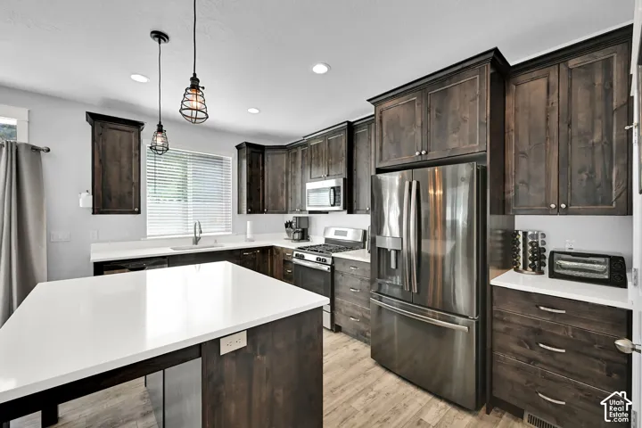Kitchen featuring dark wood-finish cabinetry, stainless steel appliances, a center island with white countertops, and recessed lighting