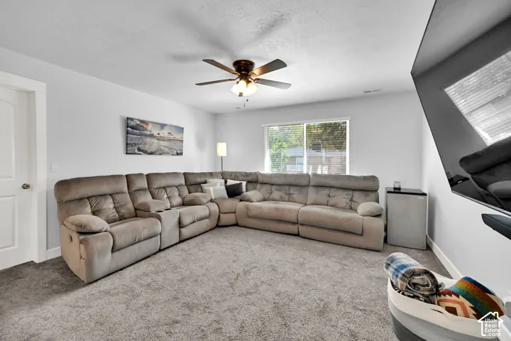 Recessed lighting, ceiling fan, white paneled door, light gray walls, and light-colored carpet flooring