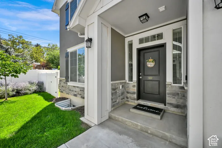 Stucco exterior with stone veneer accents, covered porch entry, transom window, and flanking sidelights