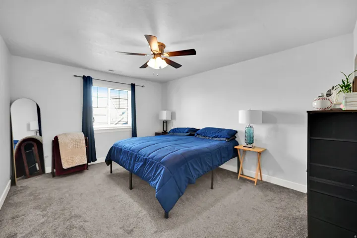 Carpeted room featuring a ceiling fan, a window with white trim, and light-colored walls