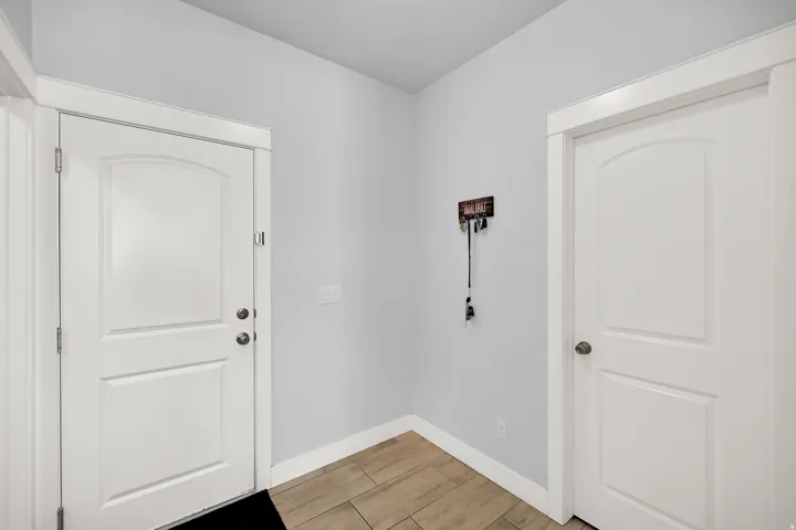 White interior doors with arched paneling, light wood-finish tile flooring, and crisp white trim