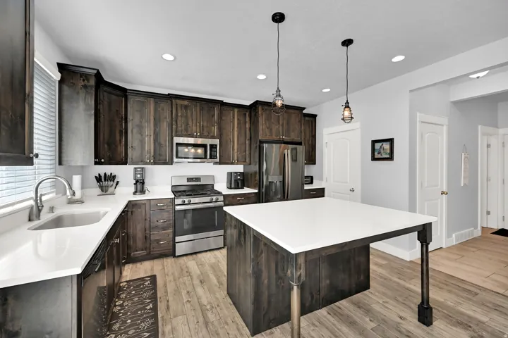 Kitchen featuring dark wood-finish cabinetry, white countertops, stainless steel appliances, and wood-finish flooring