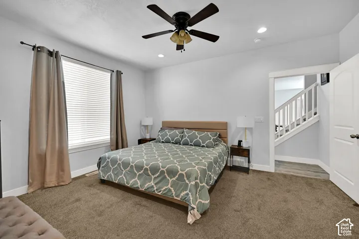 Carpeted room with a ceiling fan, recessed lighting, and a window featuring blinds