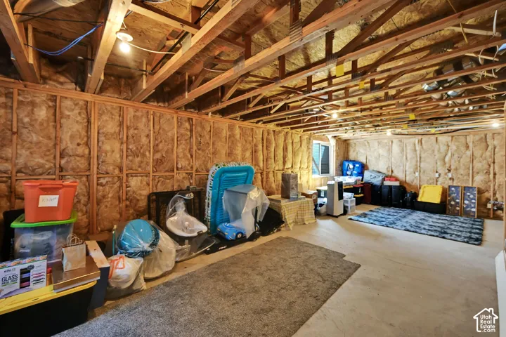 Unfinished basement with exposed ceiling joists, insulated walls, concrete flooring, and a single window