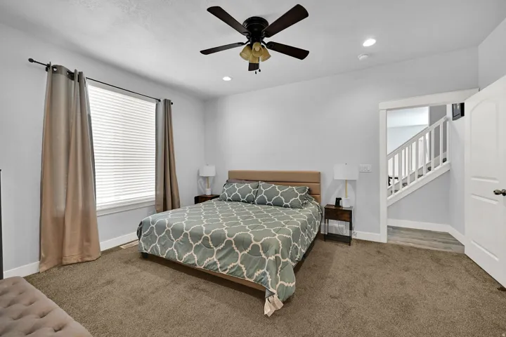 Carpeted room with a ceiling fan, recessed lighting, and a window featuring blinds