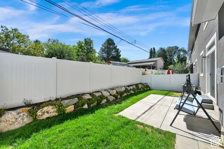 Private outdoor space featuring a concrete patio, green lawn, and white privacy fencing