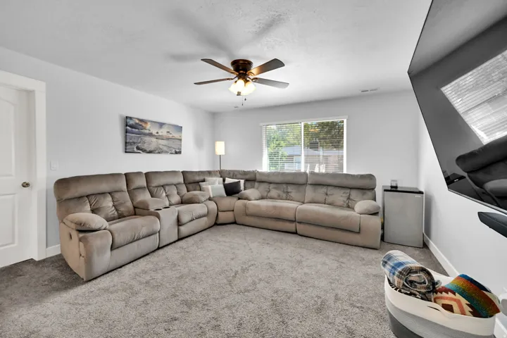 Recessed lighting, ceiling fan, white paneled door, light gray walls, and light-colored carpet flooring