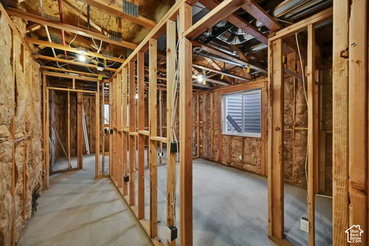 Unfinished basement featuring wood framing, exposed insulation, a concrete floor, and an egress window
