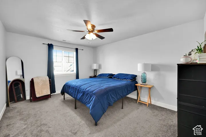 Carpeted room featuring a ceiling fan, a window with white trim, and light-colored walls