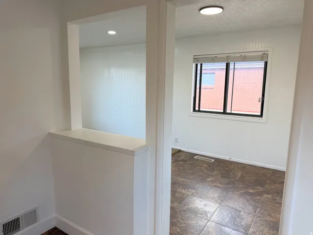 Interior pass-through window opening, recessed ceiling lighting, horizontal window with blinds, and tiled flooring