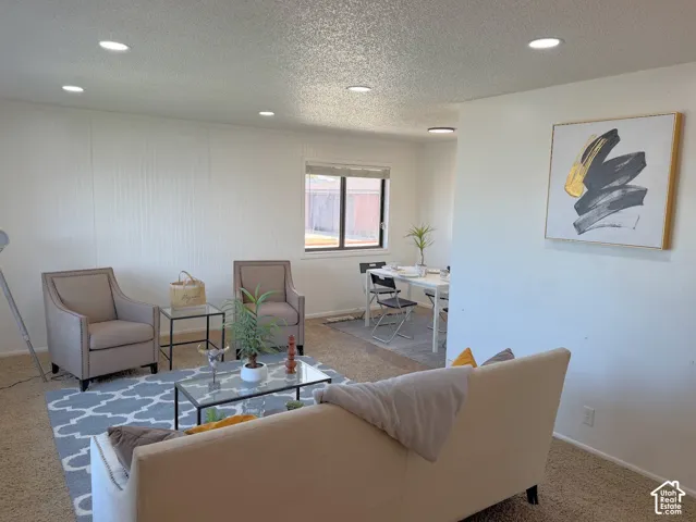 Recessed ceiling lighting illuminates the living space featuring a window with a backyard outlook, white paneled wall accents, and neutral wall tones