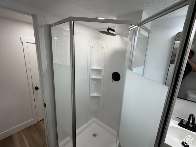 Enclosed shower with a black rain shower head and built-in shelving