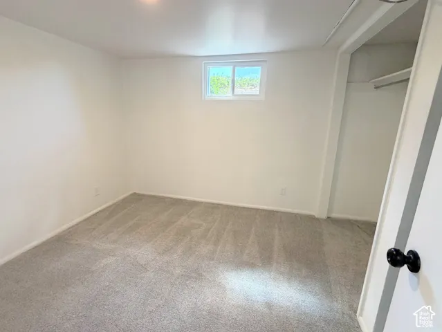 Recessed lighting, light gray carpeting, white walls, and a window with white trim