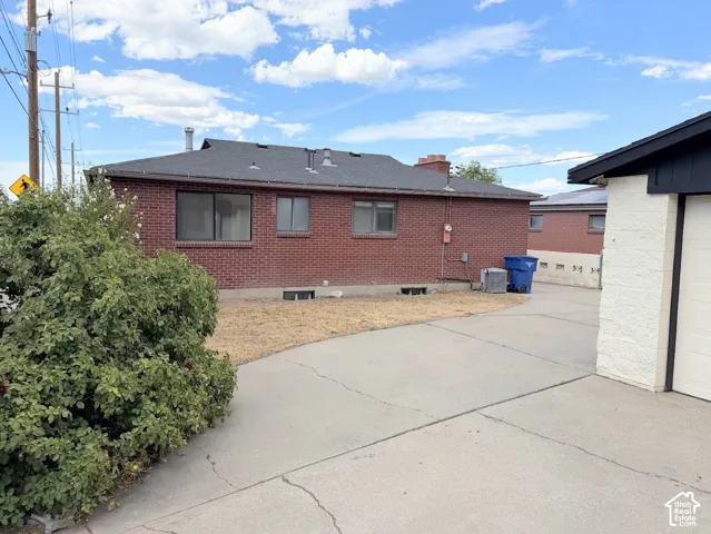 Brick exterior with a dark shingle roof, accompanied by a concrete driveway